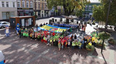 na rynek miejski przyszły najstarsze grupy Lublinieckisz przedszkolaków, za grupkami dzieci ustawionych w grupkach stoją władze lublińca z rozciągnietą flagą lublińca