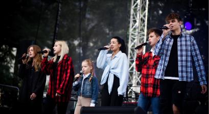 Grupa młodych artystów wykonujących utwór muzyczny na scenie 