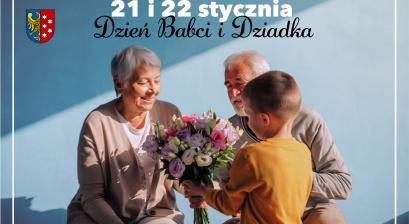 Babcia i dziadek siedzący przy niebieskiej ścianie przodem do aparatu i chłopiec wręczający bukiet kwiatów tyłem do aparatu w żółtej bluzie 