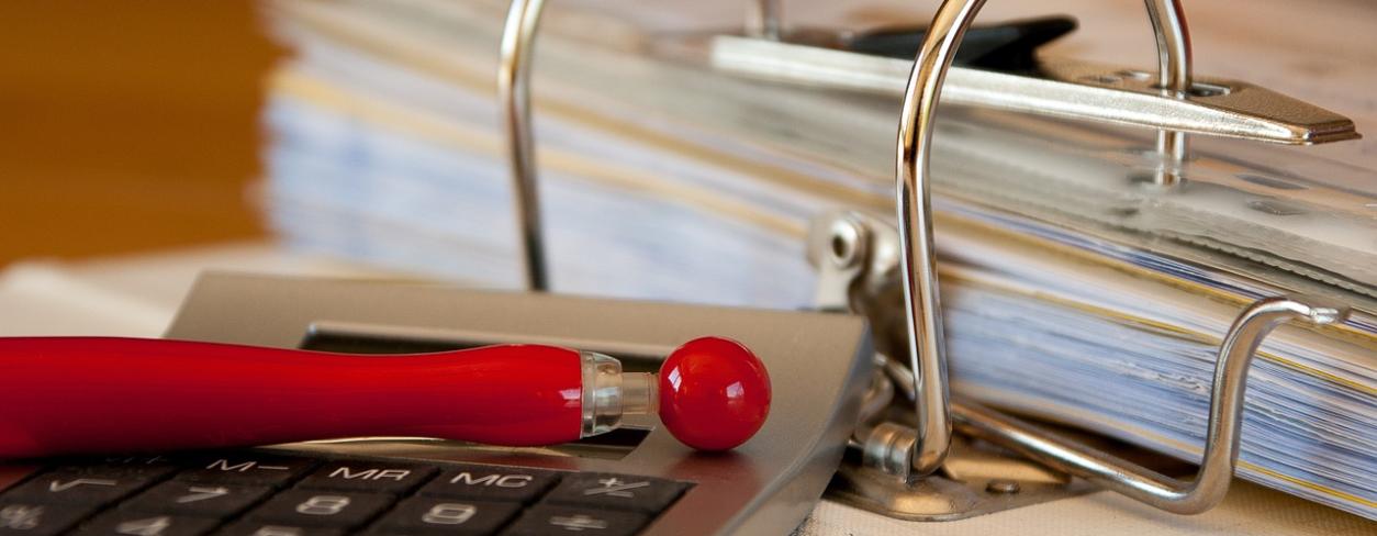 Segregator z dokumentami, długopis i kalkulator 